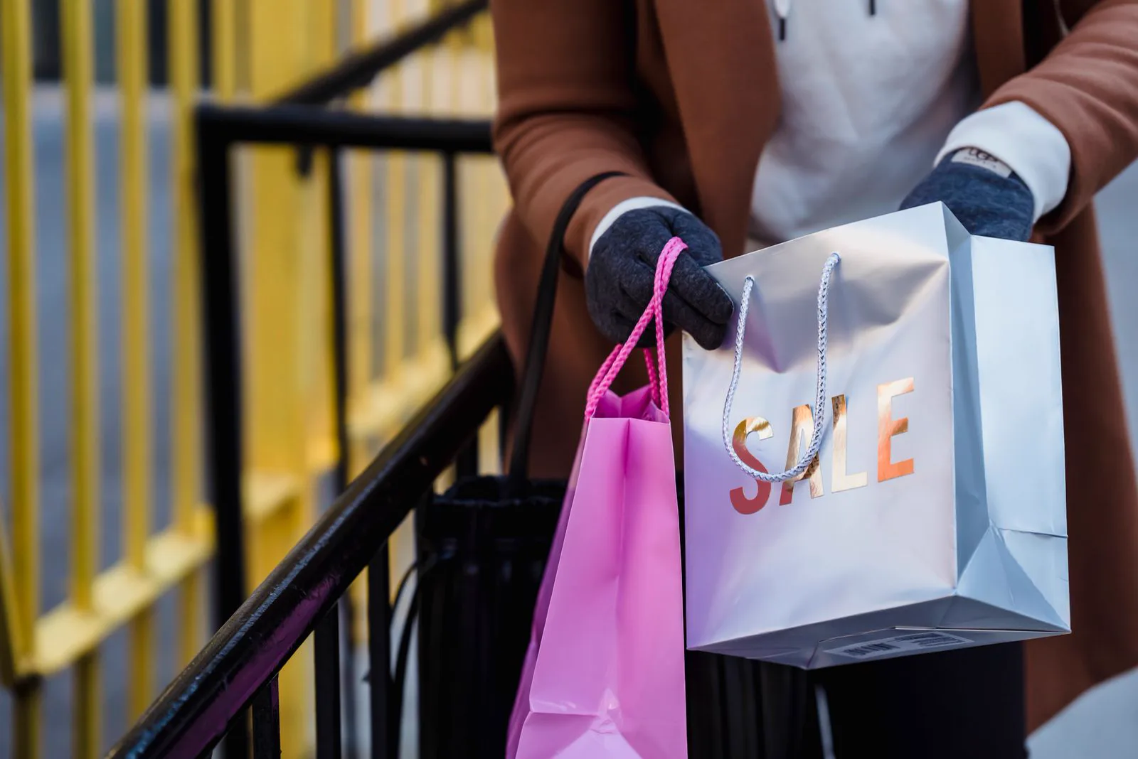 Cliente de casaco segurando sacolas de compras com a palavra sale