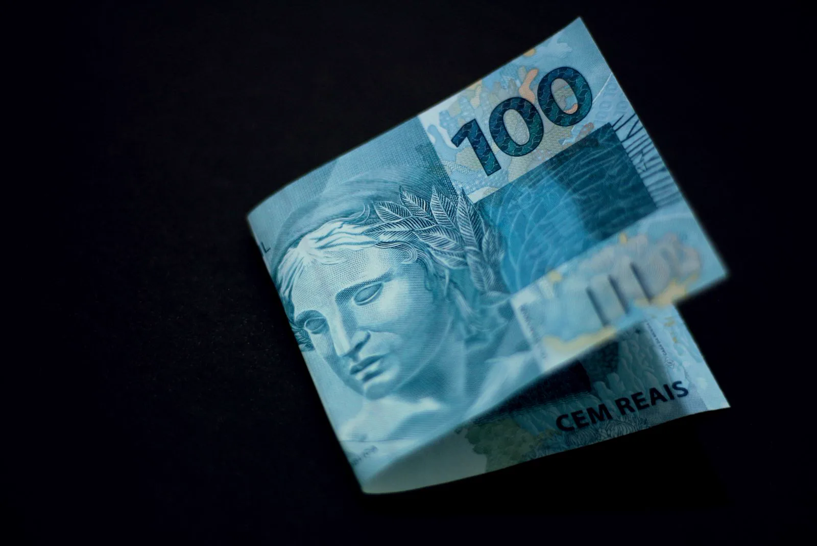 Nota de 100 reais sobre fundo preto