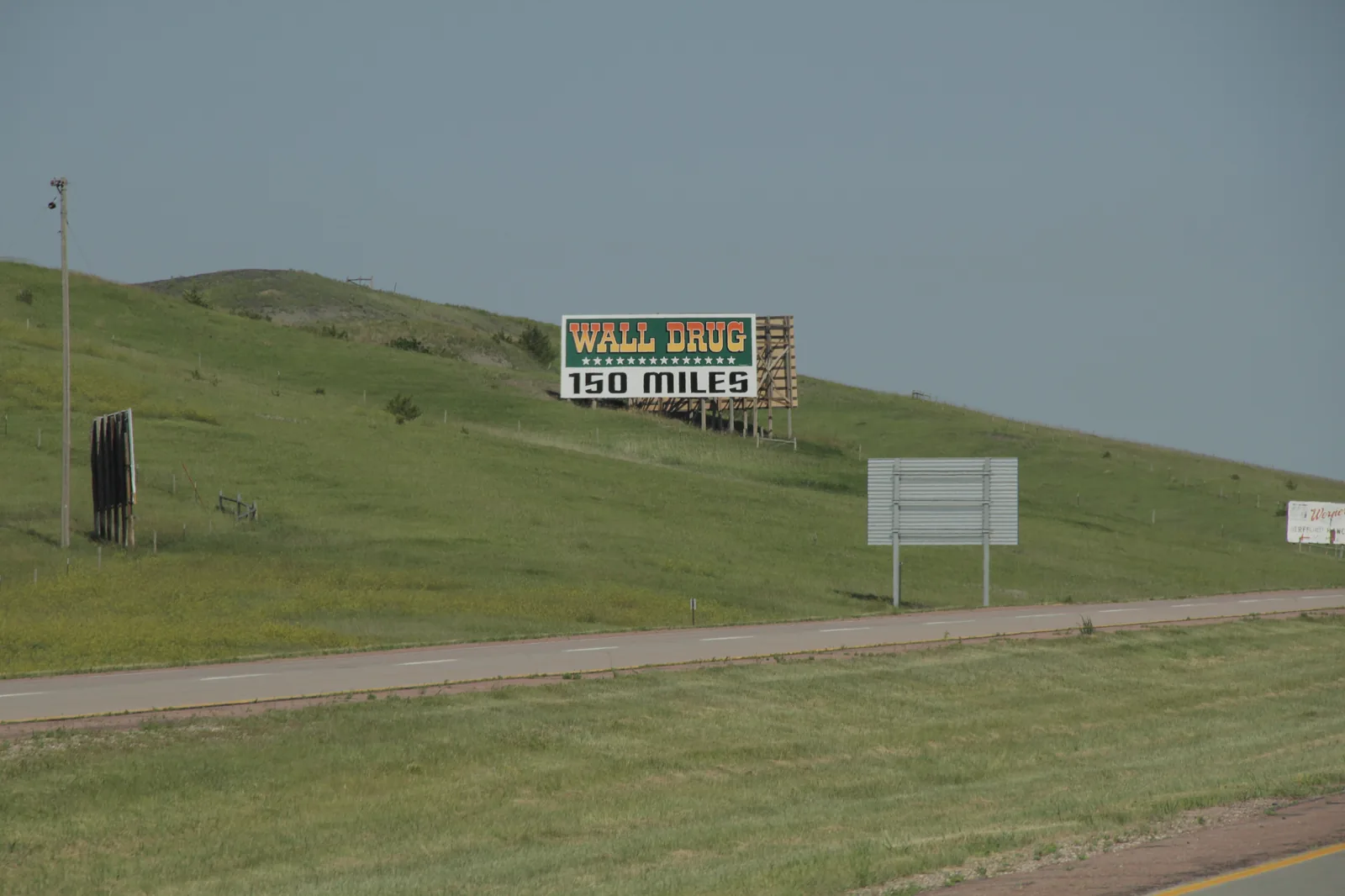 Rodovia da Dakota do Sul com outdoor da Wall Drug avisando que faltam 150 milhas até a loja