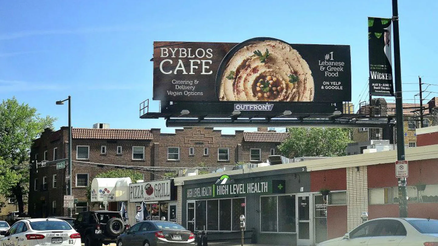 Outdoor do Byblos Cafe com um prato de homus e a frase número 1 em comida libanesa e grega no Yelp e no Google